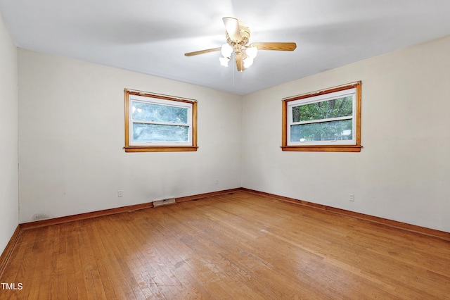 empty room with light wood-type flooring, ceiling fan, visible vents, and baseboards