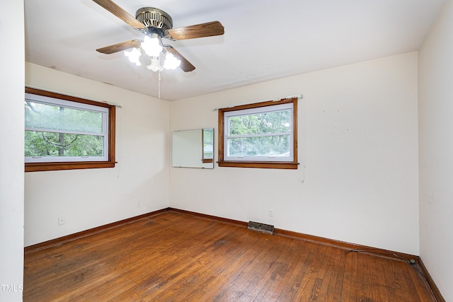 spare room with hardwood / wood-style flooring, baseboards, visible vents, and a wealth of natural light