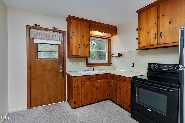 kitchen with light countertops, black range with electric cooktop, a sink, and brown cabinets