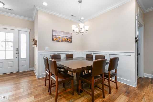 dining room with wood-type flooring, crown molding, and an inviting chandelier