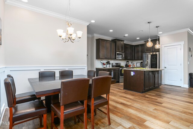 dining space with an inviting chandelier, light hardwood / wood-style floors, and ornamental molding