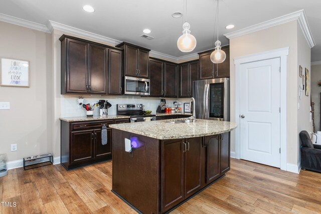 kitchen featuring an island with sink, light stone countertops, stainless steel appliances, light hardwood / wood-style flooring, and decorative light fixtures