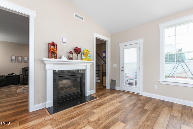 unfurnished living room with wood-type flooring, lofted ceiling, and plenty of natural light