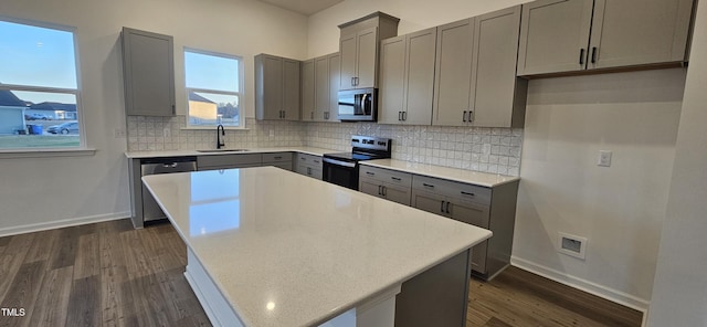 kitchen with backsplash, a kitchen island, gray cabinets, and appliances with stainless steel finishes