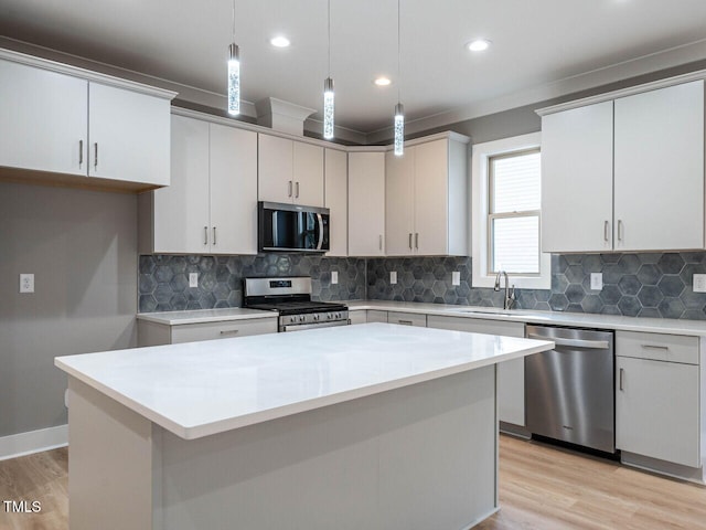 kitchen featuring pendant lighting, a center island, sink, appliances with stainless steel finishes, and white cabinetry