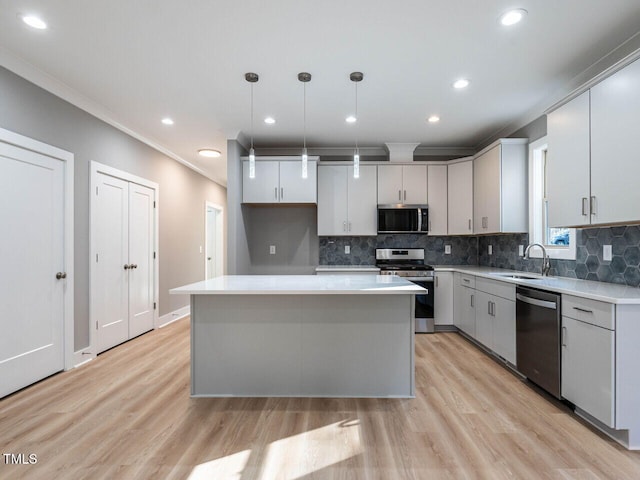 kitchen with sink, hanging light fixtures, light hardwood / wood-style floors, a kitchen island, and stainless steel appliances