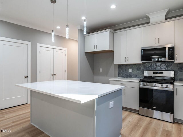 kitchen with a center island, stainless steel appliances, decorative light fixtures, and light hardwood / wood-style floors