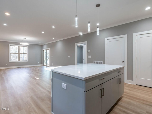 kitchen with light hardwood / wood-style flooring, a kitchen island, and hanging light fixtures