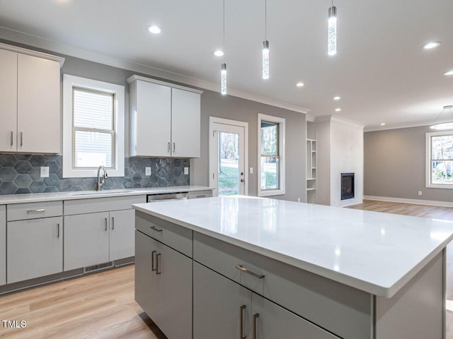 kitchen featuring light wood-type flooring, tasteful backsplash, sink, decorative light fixtures, and gray cabinets