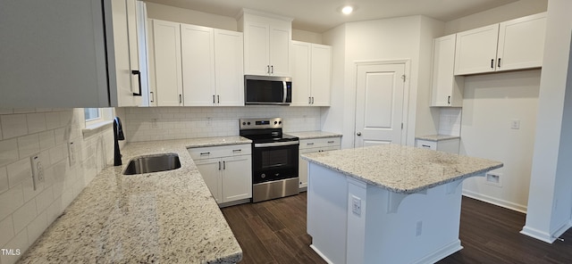 kitchen featuring sink, white cabinetry, a center island, appliances with stainless steel finishes, and light stone countertops