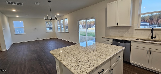 kitchen with white cabinetry, stainless steel dishwasher, decorative light fixtures, and a kitchen island