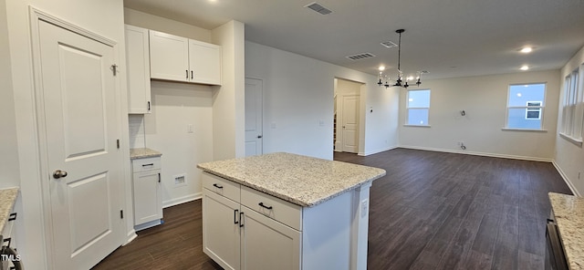 kitchen with a kitchen island, decorative light fixtures, white cabinets, dark hardwood / wood-style flooring, and light stone counters