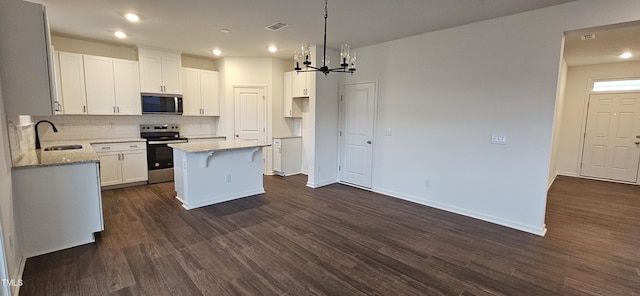 kitchen with a kitchen island, appliances with stainless steel finishes, sink, white cabinets, and light stone counters