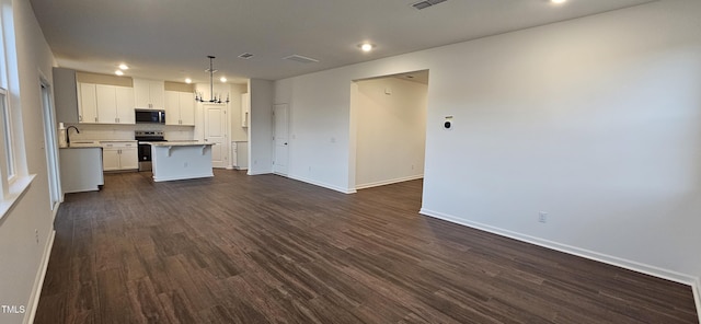 kitchen featuring dark wood-type flooring, white cabinetry, a kitchen island, pendant lighting, and stainless steel appliances