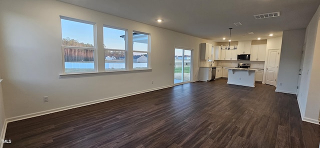 kitchen with white cabinetry, a water view, appliances with stainless steel finishes, a kitchen island, and pendant lighting