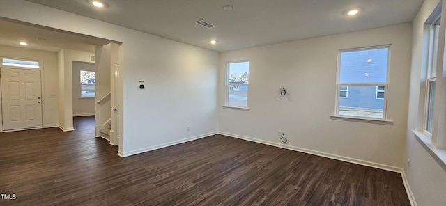 empty room with dark hardwood / wood-style flooring and a wealth of natural light