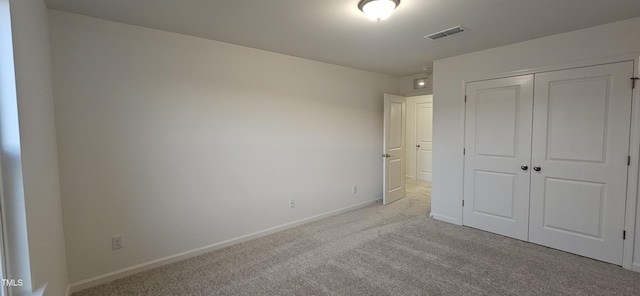 unfurnished bedroom featuring light carpet and a closet