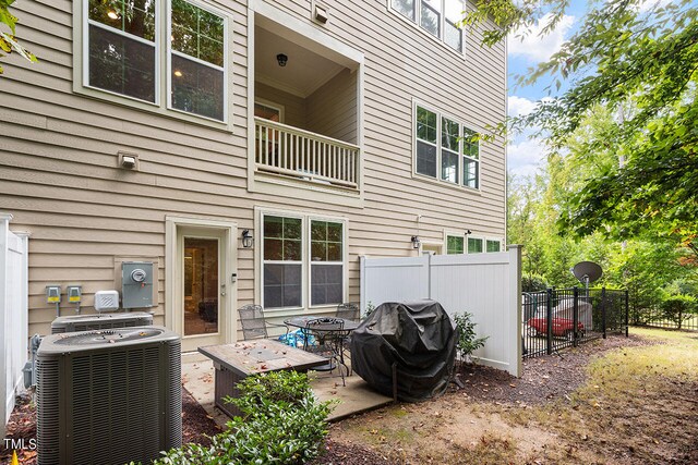 rear view of property with a balcony, a patio, and central AC