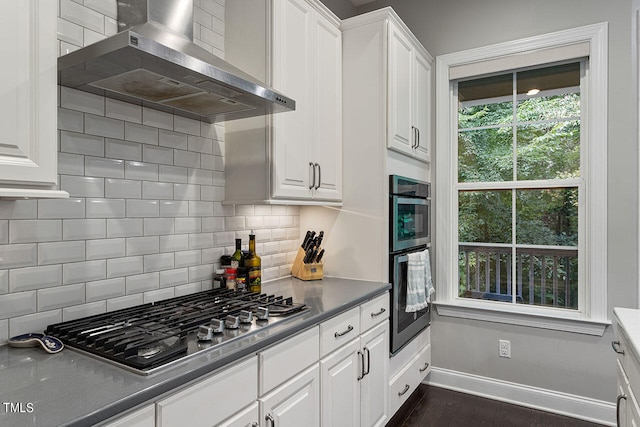 kitchen with white cabinets, dark wood-type flooring, wall chimney range hood, stainless steel appliances, and decorative backsplash