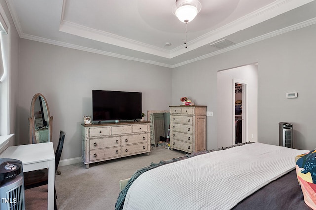 bedroom featuring a tray ceiling, a closet, light carpet, crown molding, and ceiling fan