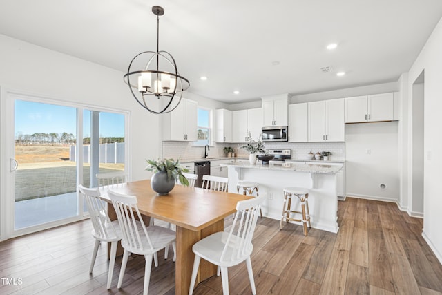 dining room with light hardwood / wood-style floors, a notable chandelier, and sink