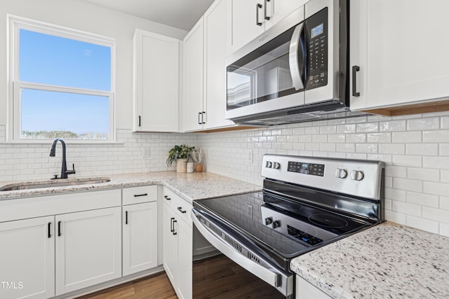 kitchen with white cabinets, backsplash, sink, and stainless steel appliances