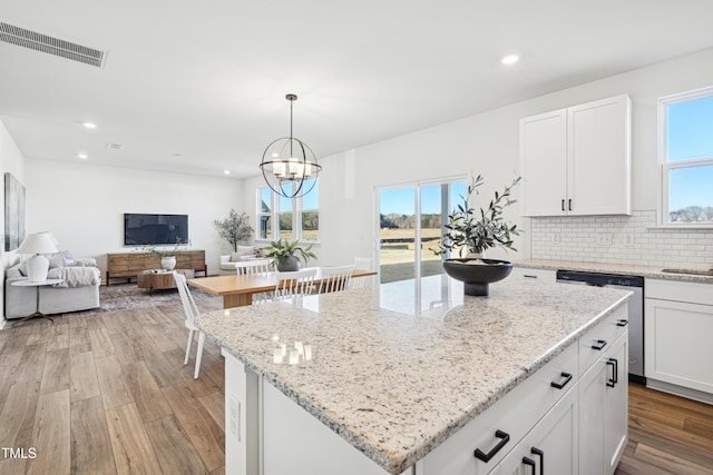 kitchen with white cabinets, a center island, decorative light fixtures, and an inviting chandelier