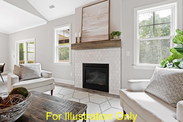 living room featuring a tiled fireplace, lofted ceiling, and light wood-type flooring