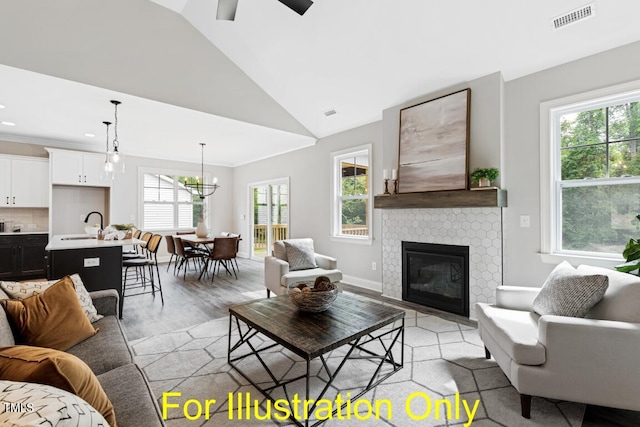 living room with vaulted ceiling, a healthy amount of sunlight, ceiling fan with notable chandelier, and a tile fireplace