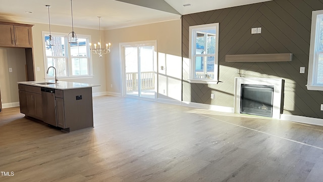 kitchen with sink, an inviting chandelier, hanging light fixtures, dishwasher, and a kitchen island with sink