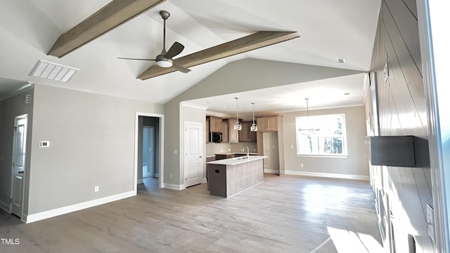 kitchen featuring pendant lighting, ceiling fan with notable chandelier, wood-type flooring, and an island with sink