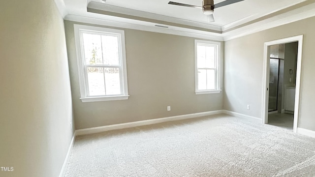 carpeted spare room with a tray ceiling, plenty of natural light, and ceiling fan