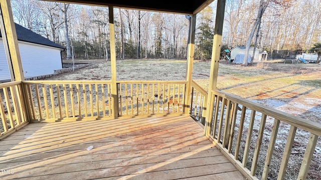 wooden deck featuring a trampoline and a storage unit