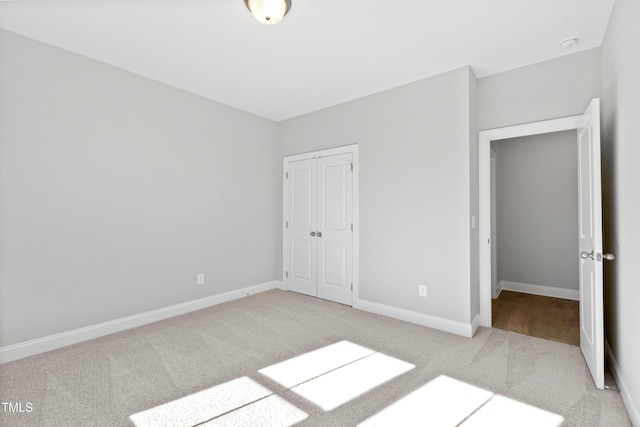 unfurnished bedroom featuring light carpet and a closet