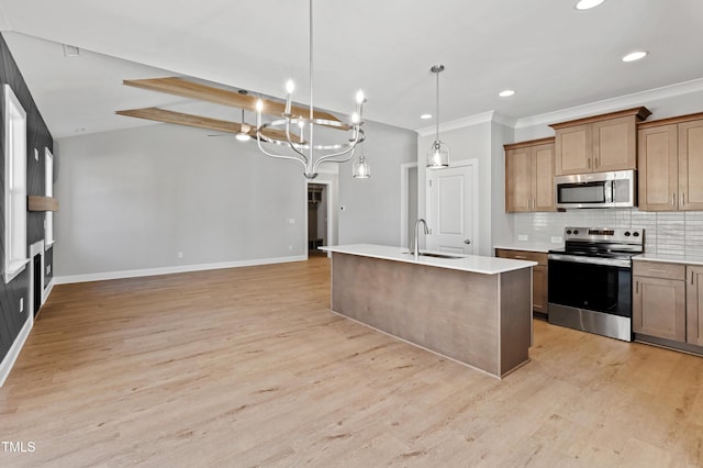 kitchen with pendant lighting, sink, backsplash, stainless steel appliances, and an island with sink