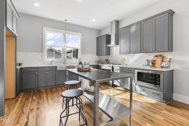 kitchen with gray cabinets, sink, wall chimney exhaust hood, and light hardwood / wood-style floors