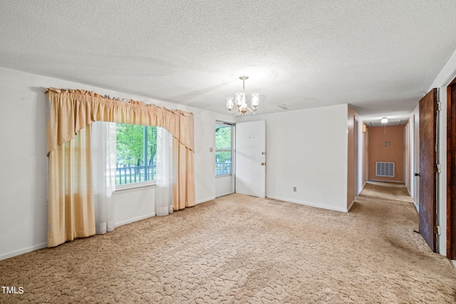 unfurnished room featuring a textured ceiling, an inviting chandelier, and carpet floors