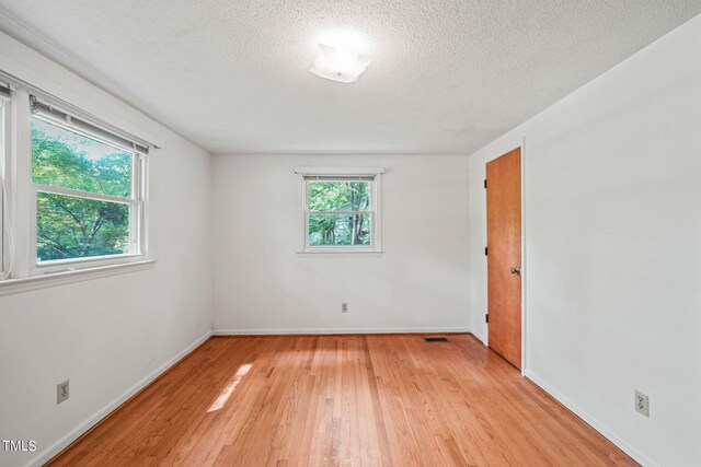 empty room featuring a textured ceiling and light hardwood / wood-style flooring