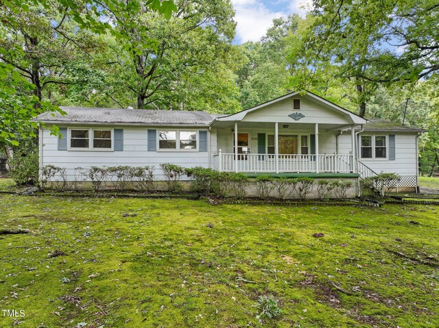 ranch-style home featuring covered porch and a front yard