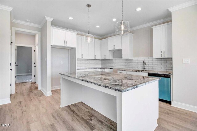 kitchen with stainless steel dishwasher, a kitchen island, sink, and white cabinetry