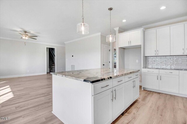 kitchen featuring white cabinets, a kitchen island, pendant lighting, light wood-type flooring, and ceiling fan