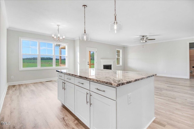 kitchen with decorative light fixtures, ceiling fan with notable chandelier, white cabinetry, and a center island