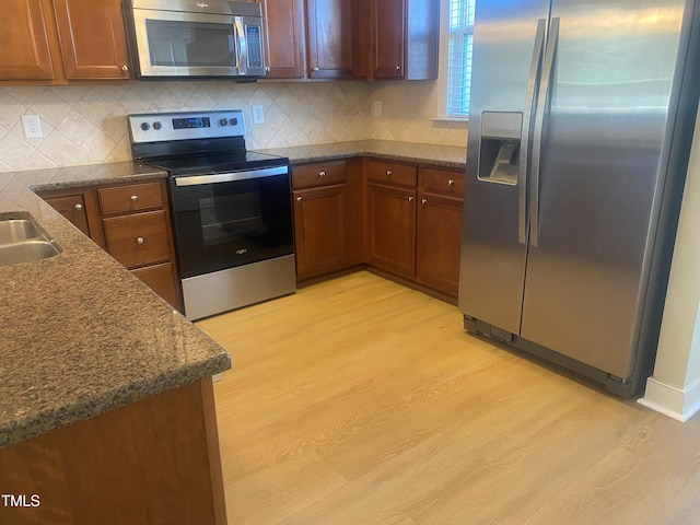 kitchen featuring light hardwood / wood-style floors, sink, backsplash, and appliances with stainless steel finishes