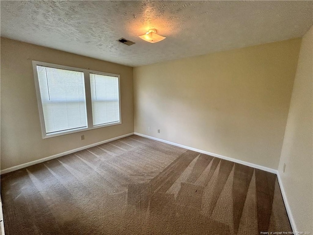 carpeted empty room featuring a textured ceiling