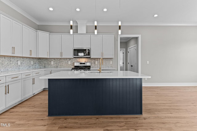 kitchen with sink, stainless steel appliances, an island with sink, light hardwood / wood-style floors, and decorative light fixtures