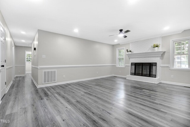 unfurnished living room featuring light wood-type flooring, a brick fireplace, ceiling fan, and a healthy amount of sunlight