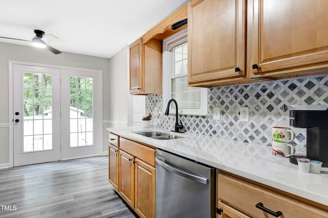 kitchen with tasteful backsplash, stainless steel dishwasher, ceiling fan, sink, and light hardwood / wood-style floors