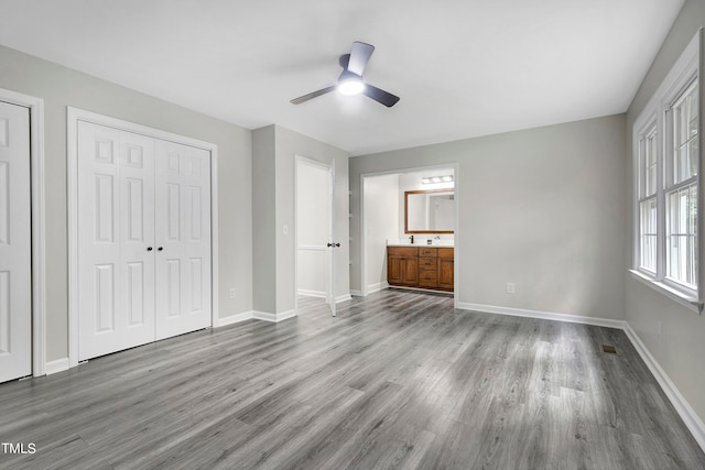 unfurnished bedroom featuring ceiling fan, wood-type flooring, and connected bathroom