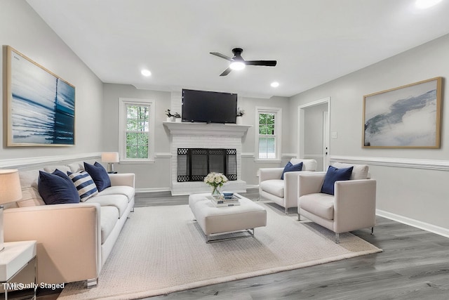 living room featuring ceiling fan, hardwood / wood-style floors, plenty of natural light, and a brick fireplace