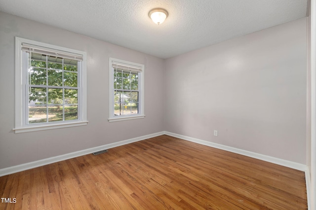 unfurnished room with a textured ceiling and hardwood / wood-style floors